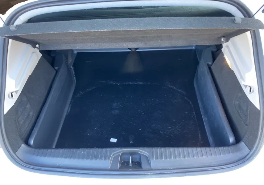 Coffre ouvert vu de dessus d’une Renault Clio V blanche, montrant un espace de rangement vide et propre.