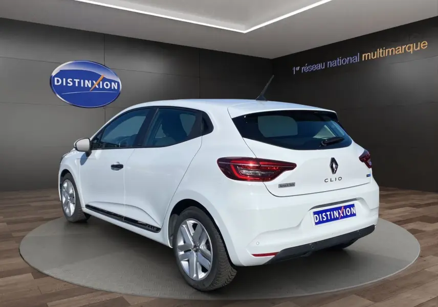 Vue 3/4 arrière droite d'une Renault Clio V blanche hybride avec logo Renault et feux arrière LED visibles.
