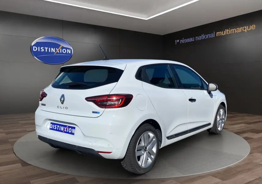 Vue 3/4 arrière droite d'une Renault Clio V blanche hybride, avec jantes alliage et logo E-TECH visible sur le hayon.