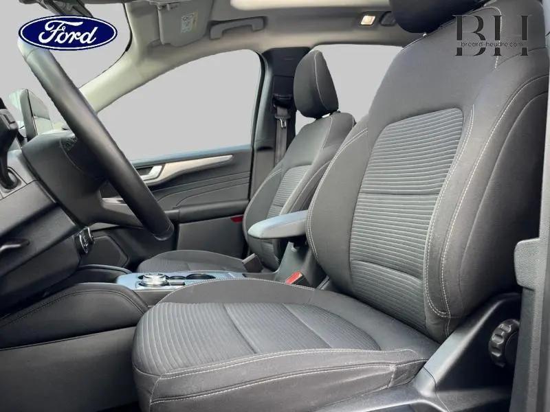 Vue intérieure côté conducteur du Ford Kuga 2022 avec sièges sport noirs et volant cuir multifonction.