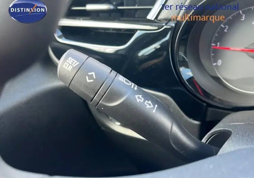 Gros plan sur la commande de clignotant noire dans l’habitacle de l’Opel Corsa gris, tableau de bord partiellement visible.