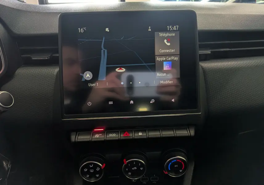 Écran tactile central avec navigation et commandes climatisation dans l’habitacle noir d’une Renault Clio V blanche.