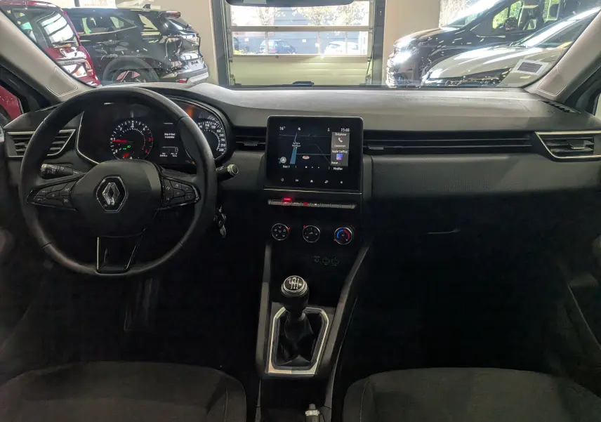 Vue intérieure frontale du tableau de bord et volant de la Renault Clio V blanche avec écran tactile et boîte manuelle.