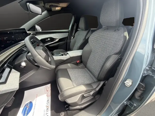 Vue intérieure côté conducteur du Peugeot 3008 bleu 2025, montrant siège tissu et cuir, tableau de bord moderne avec écran tactile.