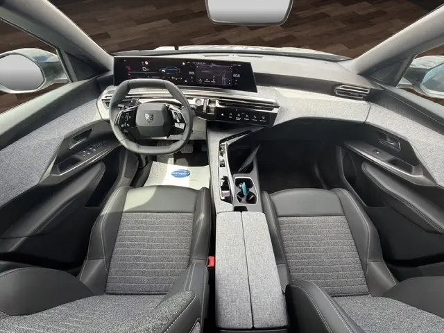 Vue intérieure avant du Peugeot 3008 bleu 2025, mettant en valeur le tableau de bord numérique et les sièges en tissu et cuir gris.