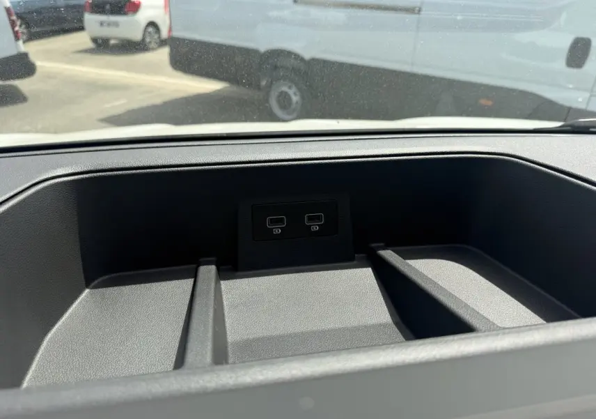 Vue rapprochée de la console centrale du Renault Trafic Fourgon 2025 avec ports USB intégrés, fond noir texturé.