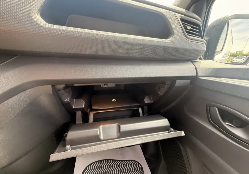 Intérieur du Renault Trafic Fourgon blanc 2025, vue sur la boîte à gants ouverte côté passager avec rangement visible.