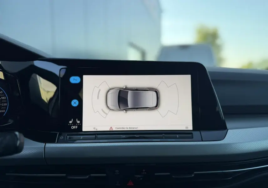 Vue intérieure sur l'écran tactile central affichant la caméra de recul de la Volkswagen Golf 8 blanche.