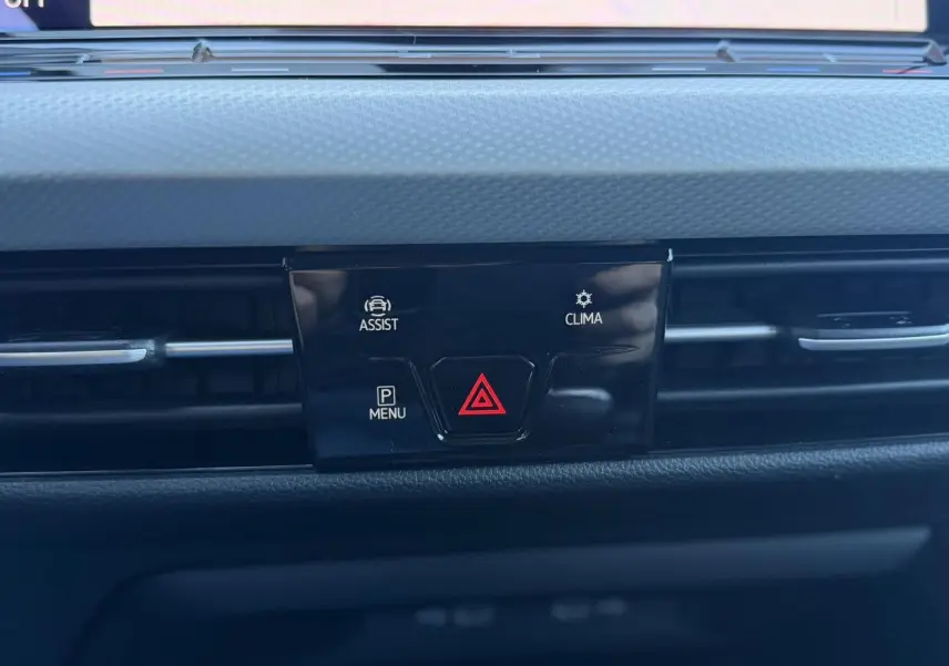 Gros plan sur la console centrale de la Volkswagen Golf 8 blanche, avec boutons d'alerte et climatisation visibles.