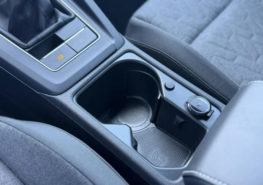 Gros plan sur la console centrale intérieure de la Volkswagen Golf 8 blanche, avec prise 12V et espace de rangement.