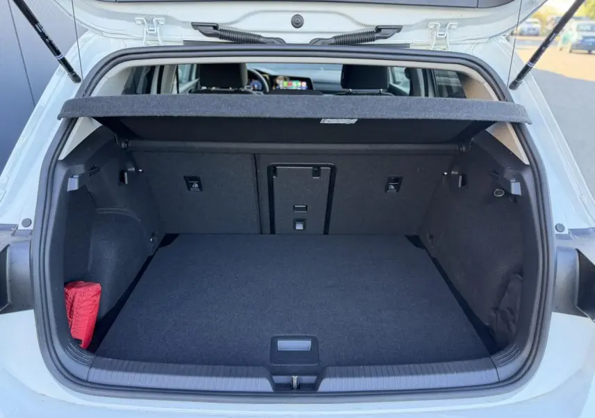 Coffre ouvert vu de l'arrière d'une Volkswagen Golf 8 blanche, montrant un espace de chargement propre et spacieux.