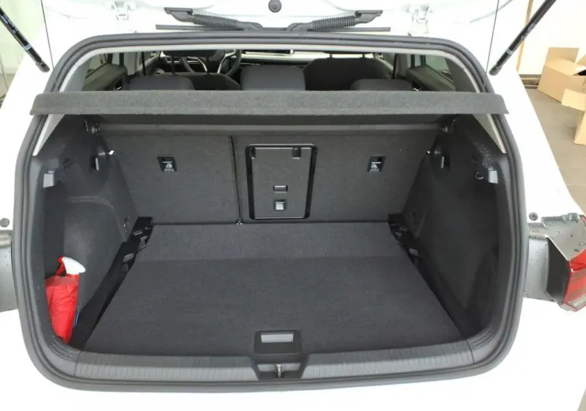 Coffre ouvert vu de l'arrière d'une Volkswagen Golf 8 blanche, montrant un espace de chargement propre et spacieux.