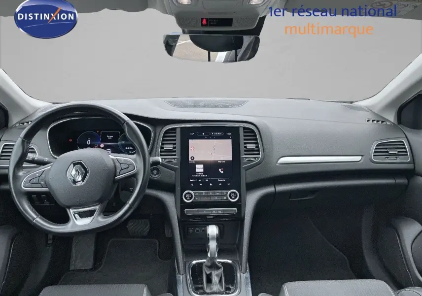 Vue intérieure frontale du tableau de bord de la Renault Mégane Break blanche Glacier, avec écran tactile central et volant multifonction.