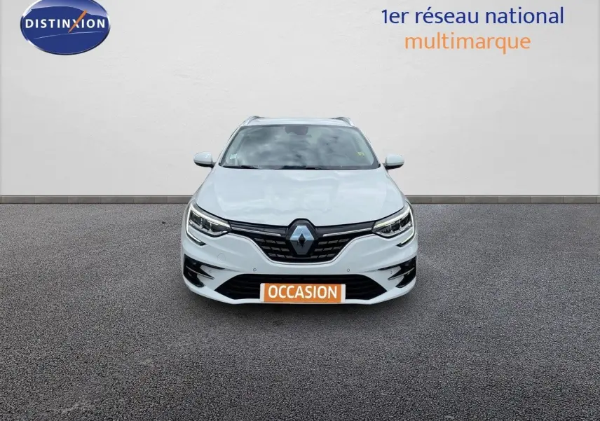Vue frontale d'une Renault Mégane Break blanche Glacier avec calandre noire et feux LED allumés.