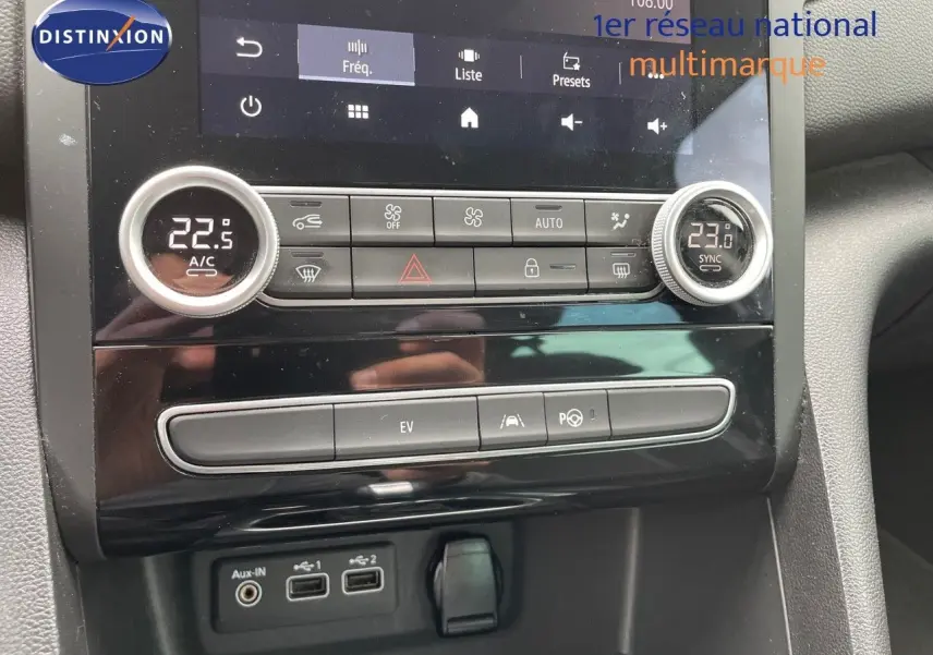 Vue intérieure centrée sur la console centrale de la Renault Mégane Break blanche, avec commandes climatisation et écran tactile.