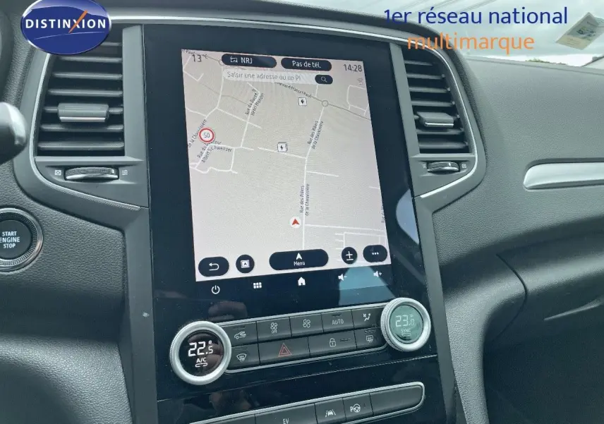 Vue rapprochée de la console centrale avec écran tactile et commandes de climatisation d’une Renault Mégane Break blanc glacier.