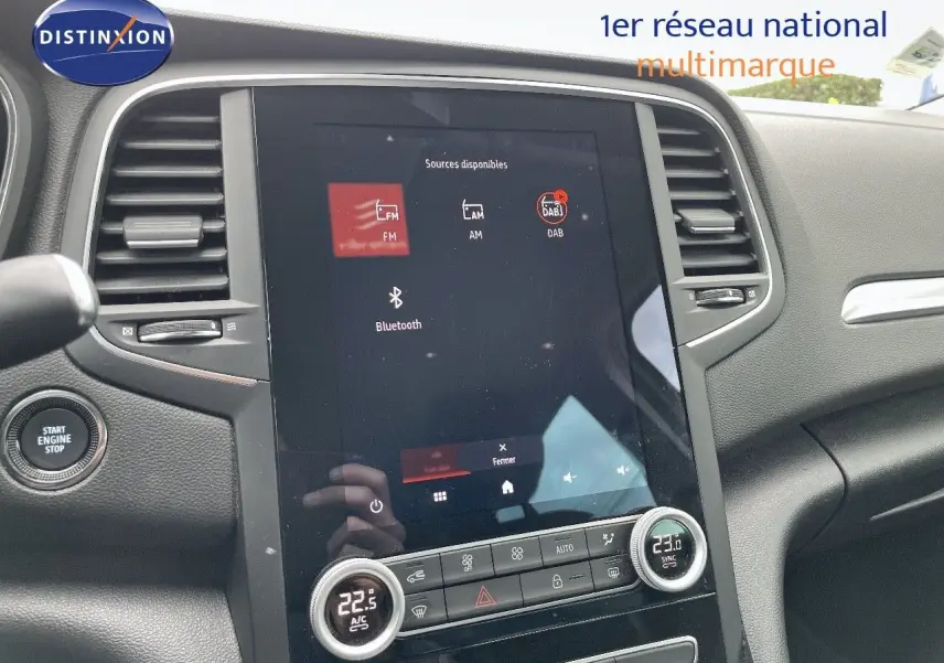 Vue intérieure centrée sur l’écran tactile et la console centrale d’une Renault Mégane Break blanc glacier, version hybride rechargeable.