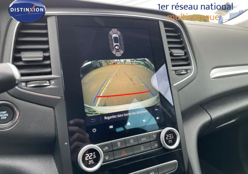 Vue intérieure du tableau de bord de la Renault Mégane Break blanc glacier, avec écran tactile affichant la caméra de recul.
