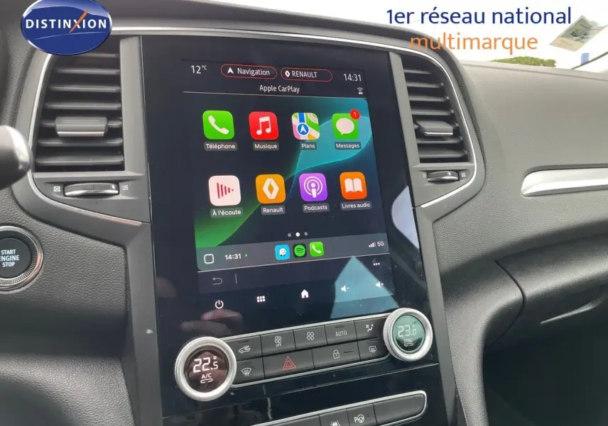 Vue intérieure centrée sur l'écran tactile du tableau de bord de la Renault Mégane Break blanc glacier, affichant Apple CarPlay.