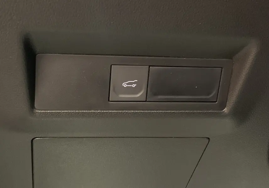 Bouton d'ouverture du hayon motorisé mains libres sur la garniture intérieure du coffre du Renault Symbioz bleu iron.