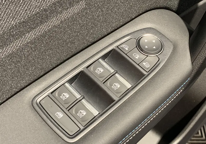 Gros plan sur les commandes de lève-vitres et rétroviseurs avec surpiqûres bleues dans une Renault Symbioz Bleu Iron.