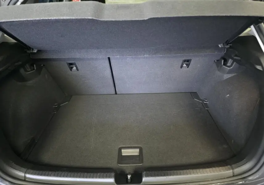 Coffre ouvert vu de l'arrière d'une Volkswagen Polo gris, montrant l'espace de chargement et la banquette arrière rabattable.