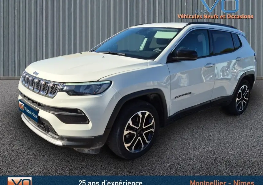 Jeep Compass blanc en 3/4 avant droit, avec jantes 18 pouces et rétroviseurs noirs sur fond urbain.