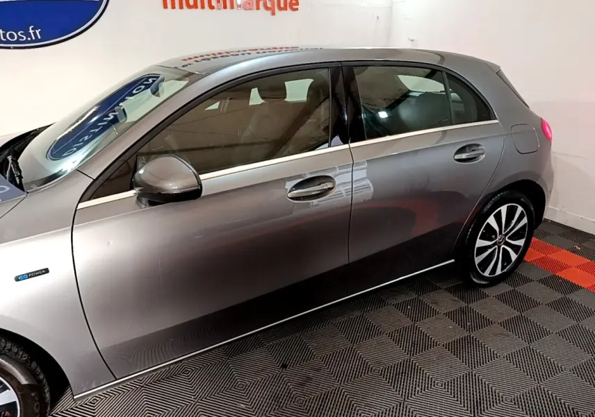 Vue latérale droite d'une Mercedes Classe A 250 e Business Line gris foncé avec jantes distinctives et logo EQ Power.