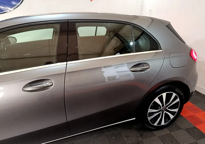 Profil côté droit d'une Mercedes Classe A 250 e Business Line gris foncé, avec jante alliage et feux arrière visibles.