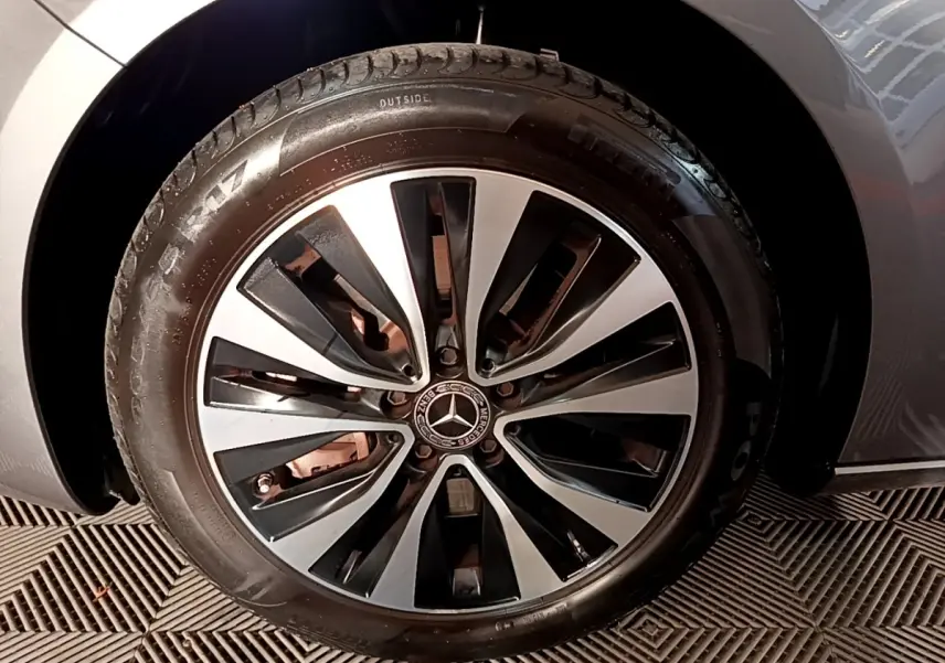 Gros plan sur la roue avant gauche d'une Mercedes Classe A gris foncé avec jante alliage bicolore au design moderne.