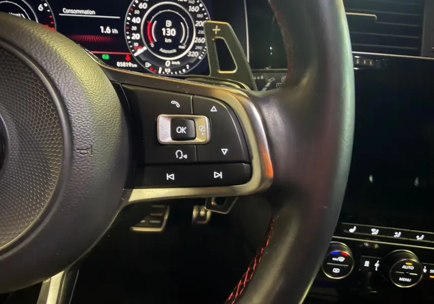 Gros plan sur le volant sport noir avec surpiqûres rouges et commandes multifonctions du Volkswagen Golf GTI Performance 2018.