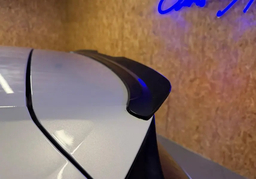 Gros plan sur l'aileron arrière noir d'une Volkswagen Golf GTI Performance gris, vue depuis le côté gauche arrière.