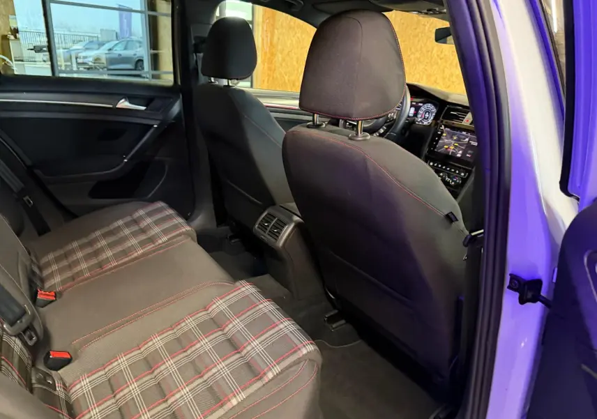 Vue intérieure sur la porte arrière droite ouverte d'une Volkswagen Golf GTI Performance grise, avec garniture noire et éclairage bleu subtil.