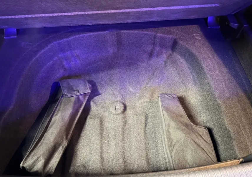 Coffre ouvert de Volkswagen Golf GTI Performance gris, vue plongeante sur le rangement sous plancher avec housses noires.