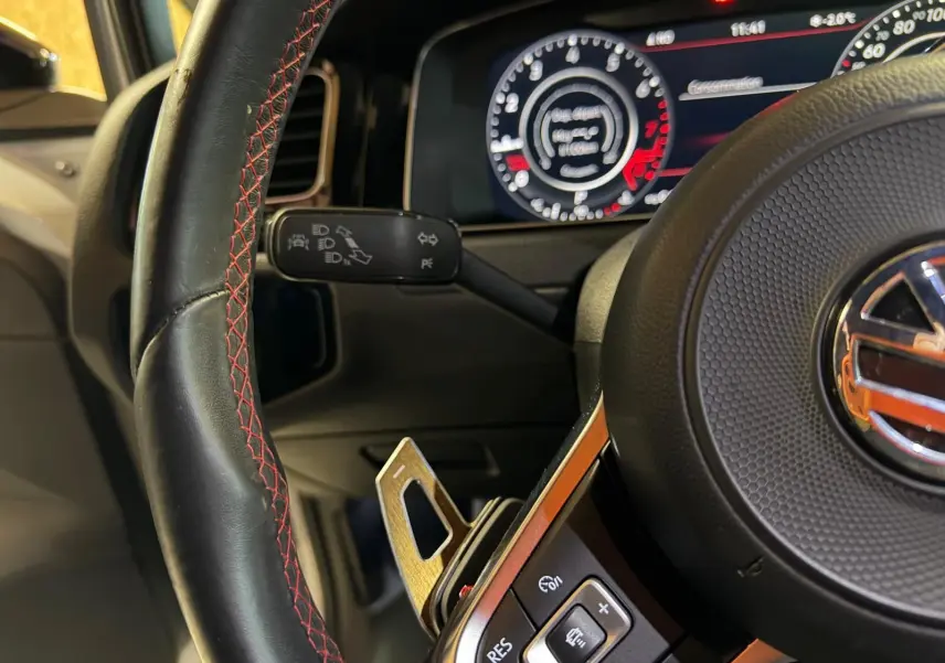 Vue intérieure côté conducteur d’une Volkswagen Golf GTI Performance 2018 avec sièges sport à motif tartan et coutures rouges.