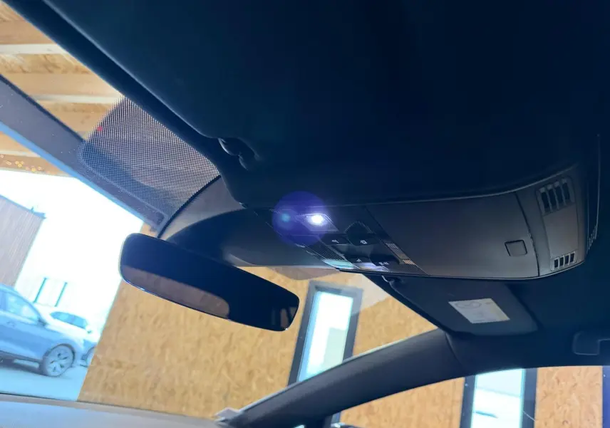 Gros plan sur l'emblème GTI rouge sur la portière côté gauche d'une Volkswagen Golf gris clair.