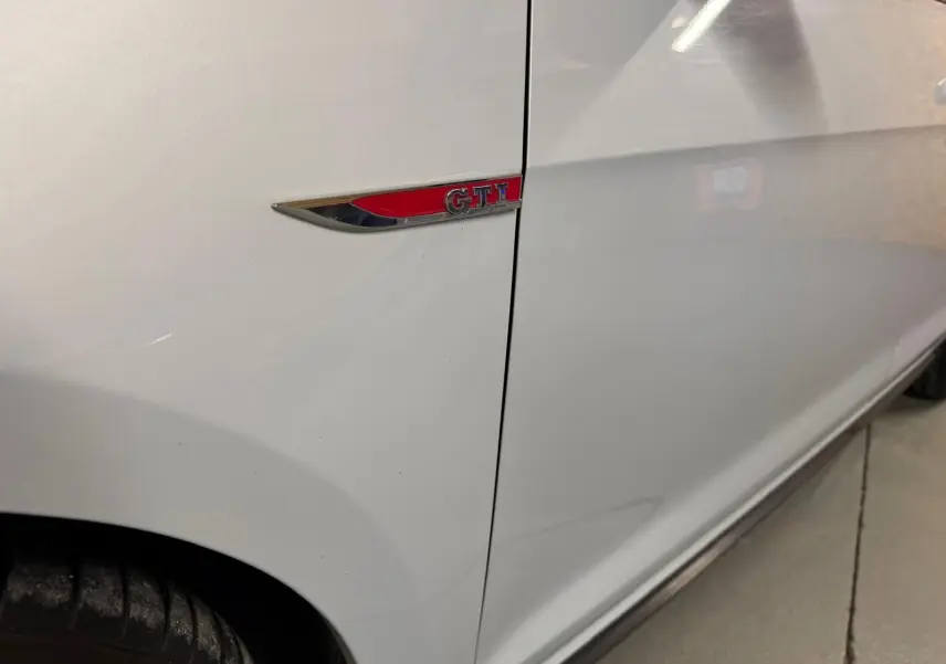 Gros plan sur la roue avant gauche gris clair d'une Volkswagen Golf GTI Performance avec étrier de frein rouge et jante alu 19 pouces.
