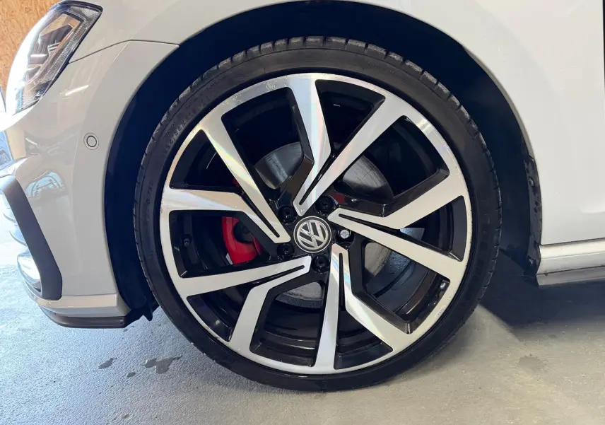 Gros plan sur la roue avant droite gris clair de la Volkswagen Golf GTI Performance avec étrier de frein rouge et jante alu 19 pouces.