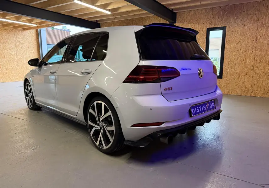 Vue 3/4 arrière droite d'une Volkswagen Golf GTI Performance gris clair avec jantes alu 19'' et sorties d'échappement chromées.