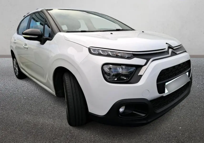 Citroën C3 blanc vue 3/4 avant droit, avec phares distinctifs et calandre noire contrastante.