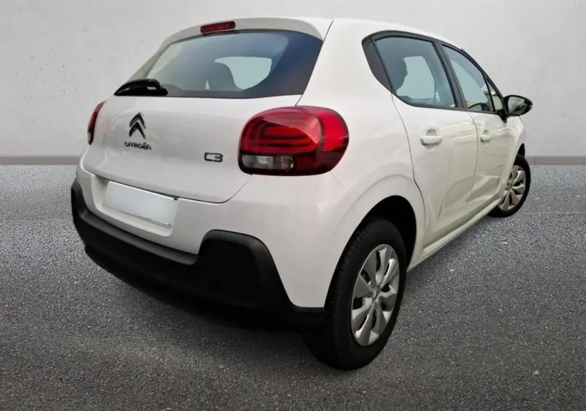 Vue 3/4 arrière droite d'une Citroën C3 blanche 2021 avec feux arrière rouges et pare-chocs noir contrastant.