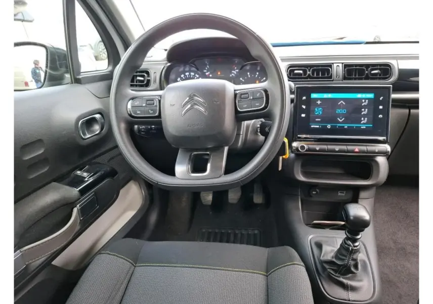 Vue intérieure centrée sur le volant et la console centrale tactile d'une Citroën C3 blanche, version 2021.