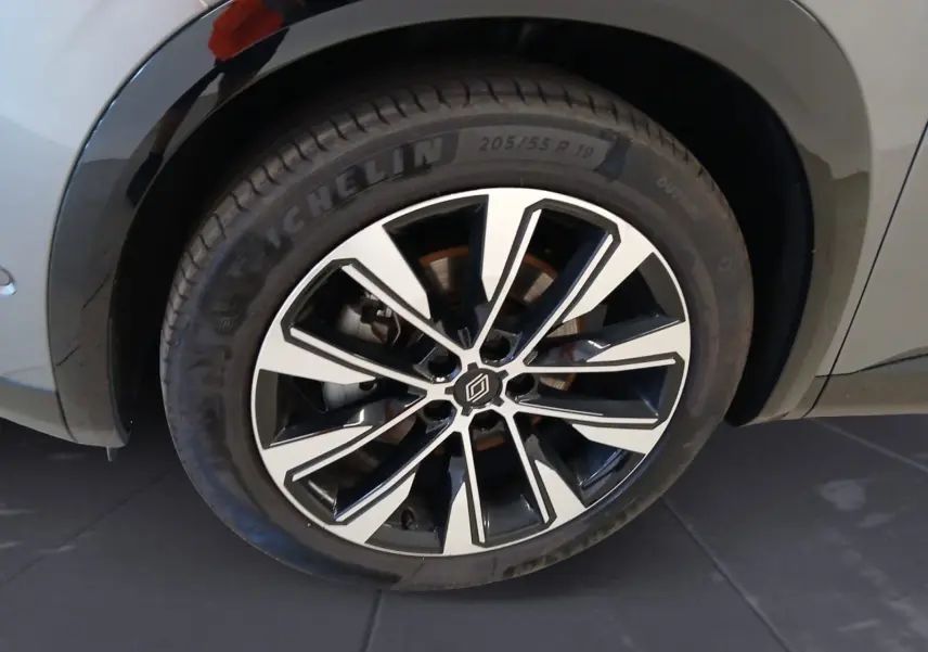 Gros plan sur la roue alliage 19'' Komah diamantée noir du côté gauche du Renault Austral gris clair.