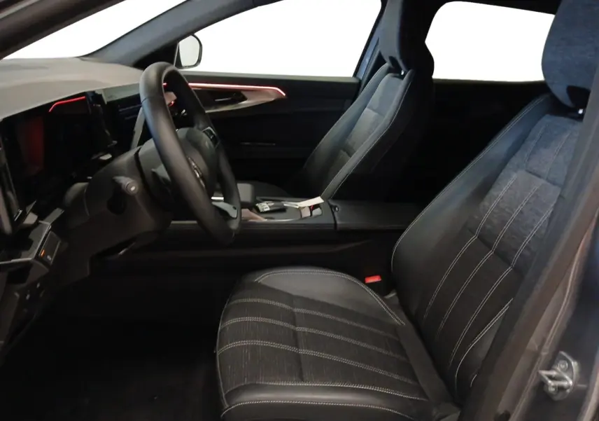 Intérieur Renault Austral E-Tech 2024 vu côté conducteur, sièges tissu gris et éclairage d'ambiance rouge sur porte.