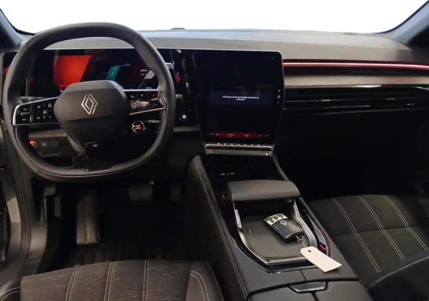 Vue intérieure avant du Renault Austral 2024, tableau de bord noir avec écran tactile vertical et volant multifonction.