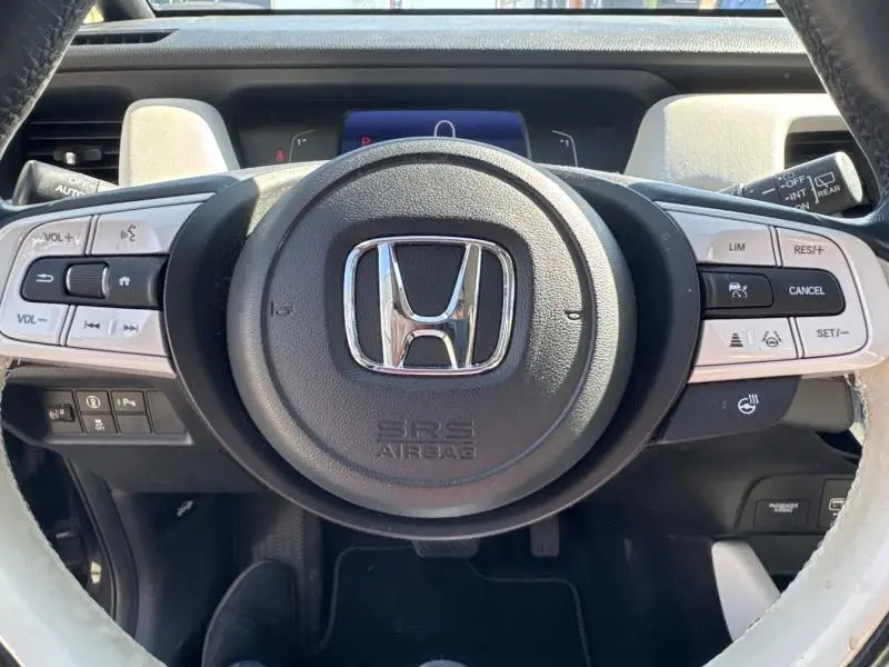 Vue rapprochée du volant cuir noir et blanc de la Honda Jazz 2021 avec commandes multifonctions intégrées.