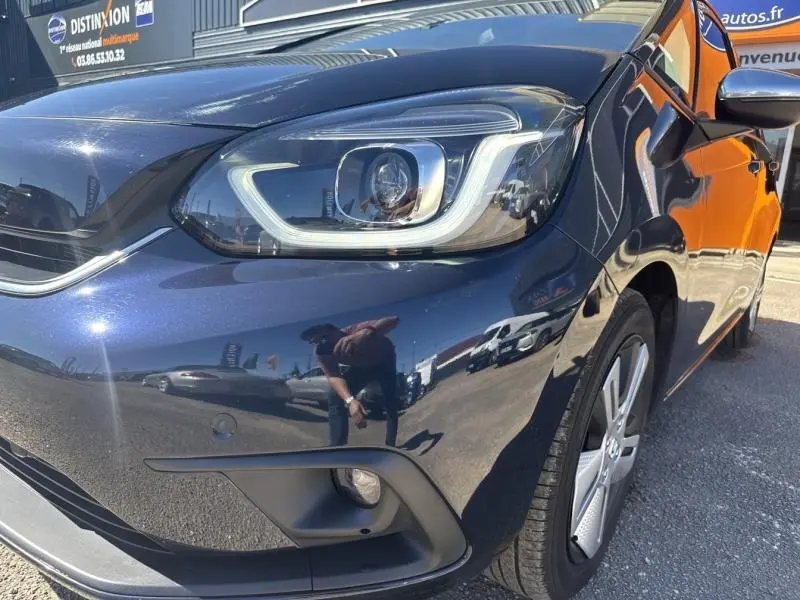 Vue 3/4 avant droit d'une Honda Jazz 1.5 i-MMD bleu nuit nacré avec phares LED et jantes alu visibles.