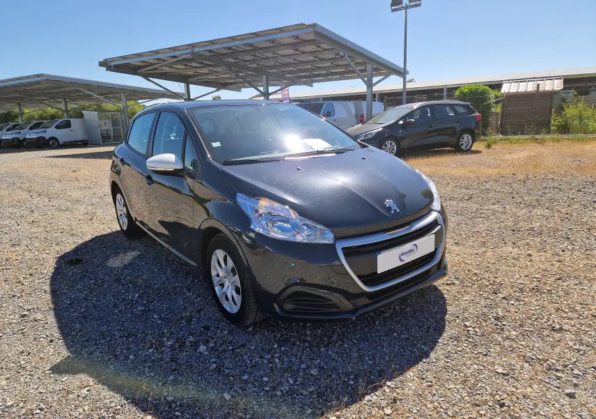 Peugeot 208 gris hurricane vue 3/4 avant droit sur parking, avec rétroviseurs blancs et jantes alliage.