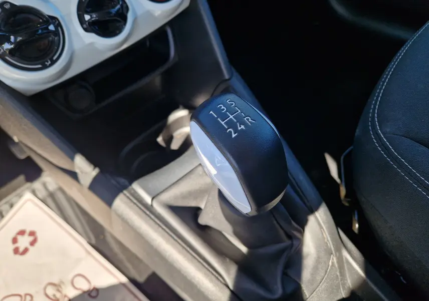 Gros plan sur le levier de vitesse manuel noir et blanc de la Peugeot 208 gris Hurricane, avec console centrale et sièges visibles.