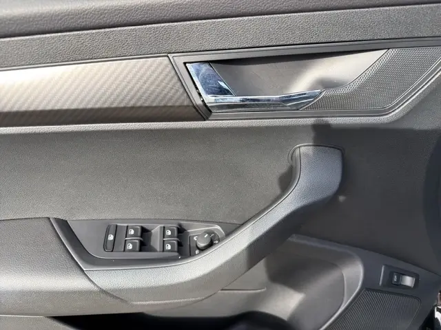 Détail de la porte intérieure côté conducteur du Skoda Karoq noir 2025, avec commandes électriques des vitres et poignée chromée.